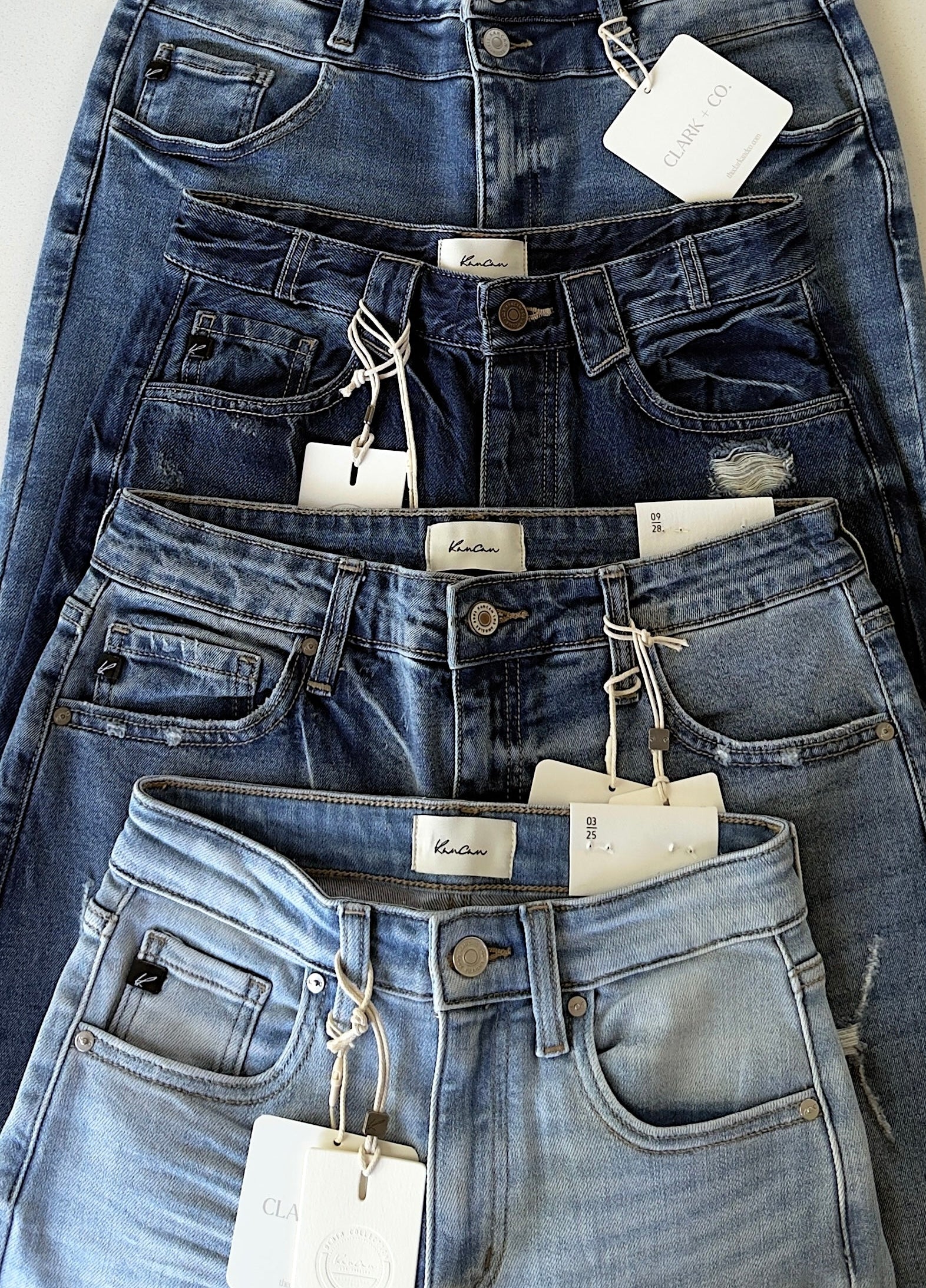 pairs of blue jeans with tags on a light background

